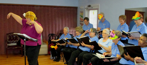 Photo shows Mary Kate and some of the singers wearing hats with animal masks while singing.
